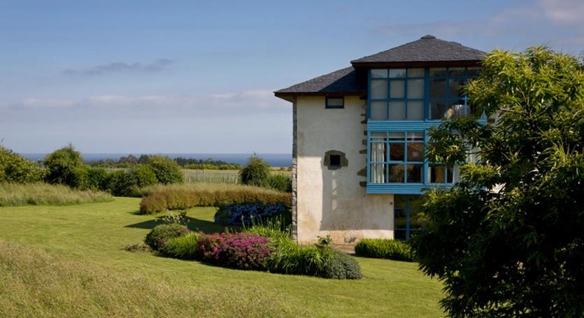 una casa con una gran ventana en un campo en Hotel Torre De Villademoros, en Luarca