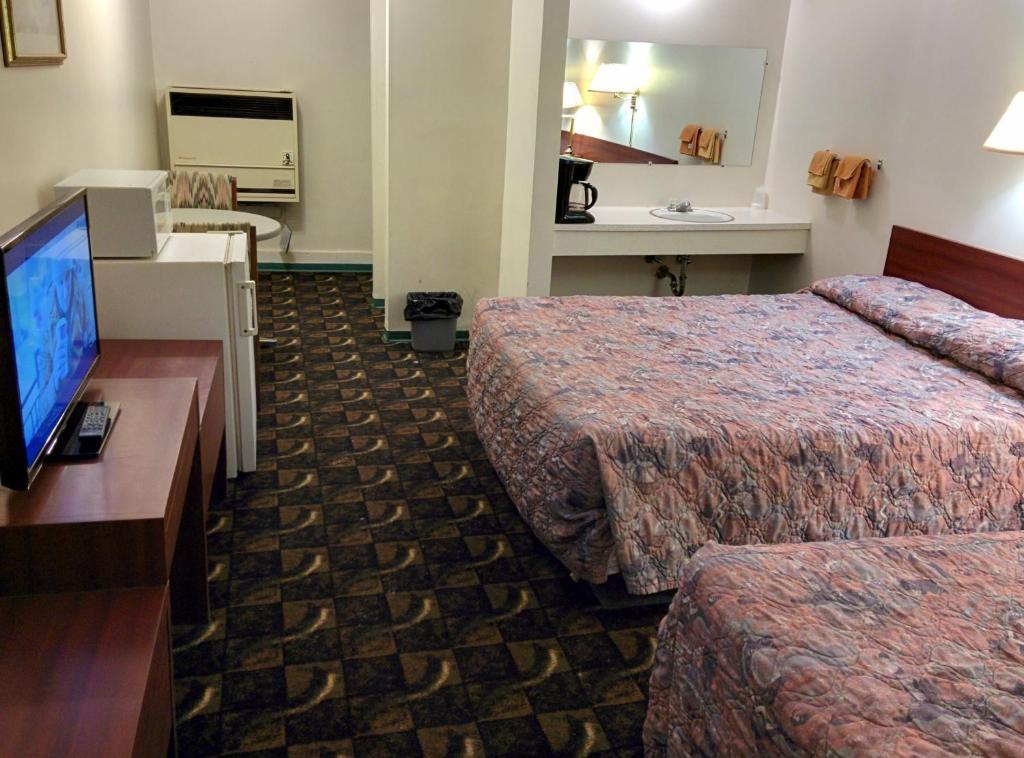 a hotel room with two beds and a flat screen tv at Shamrock Motel in Valleyview