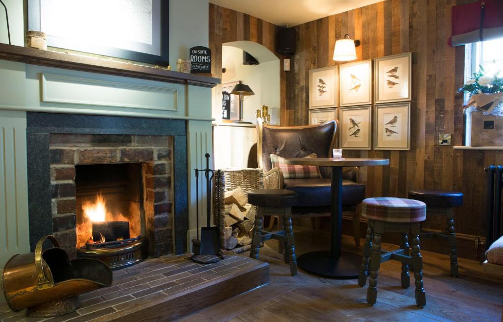 a living room with a fireplace and a table and chairs at Red Lion Inn in Little Budworth