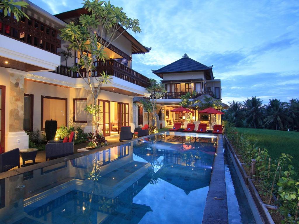 a house with a swimming pool in front of a house at Uma Stana Villa in Ubud