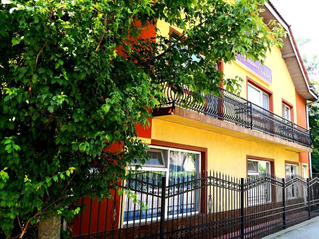 żółto-pomarańczowy budynek z czarnym płotem w obiekcie Golden Pension w mieście Târgu Jiu