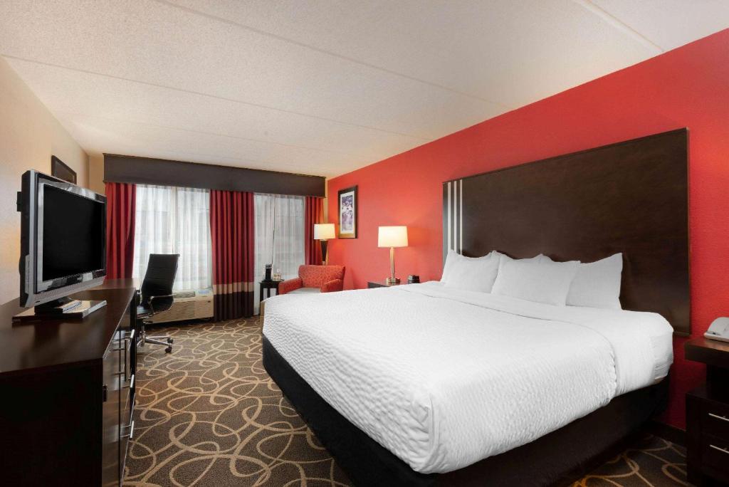a hotel room with a bed and a flat screen tv at La Quinta Inn & Suites - New River Gorge National Park in Summersville