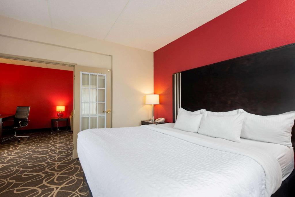 a large bed in a hotel room with a red wall at La Quinta Inn & Suites - New River Gorge National Park in Summersville