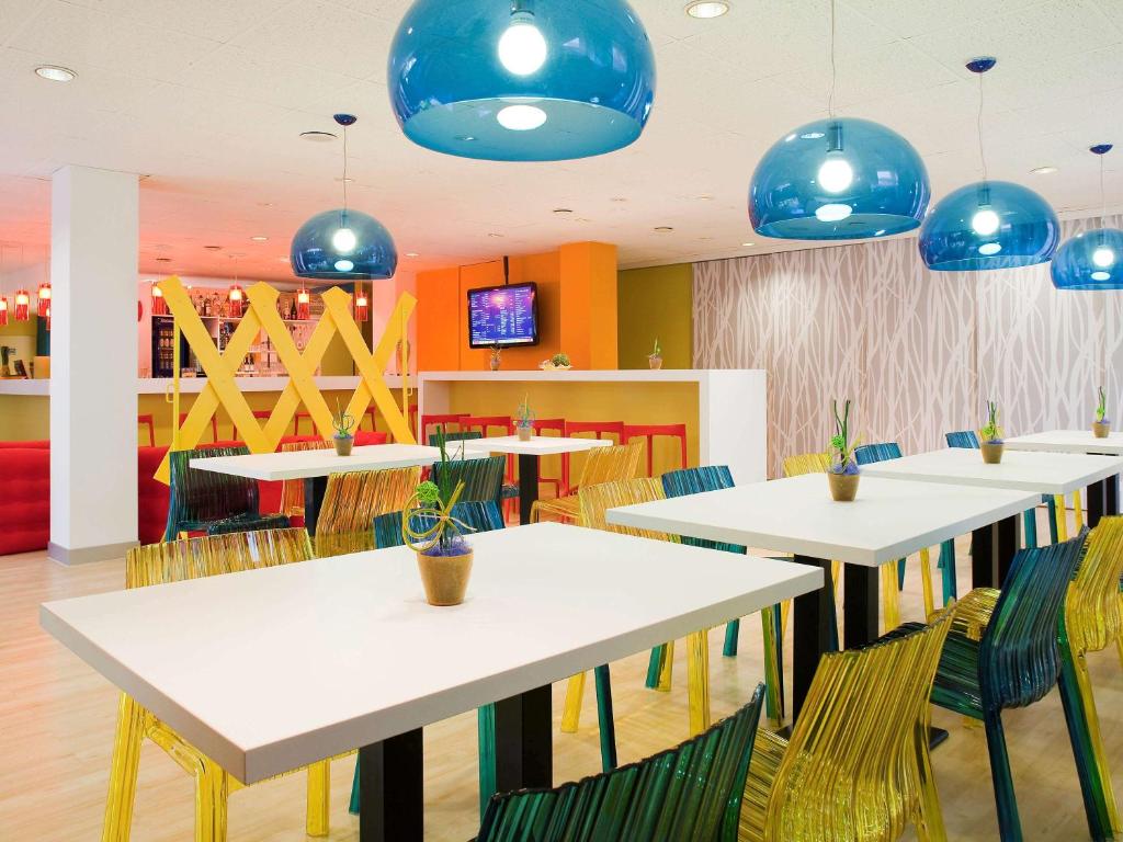 une salle à manger avec des tables, des chaises et des lumières bleues dans l'établissement ibis Styles Duesseldorf-Neuss, à Neuss