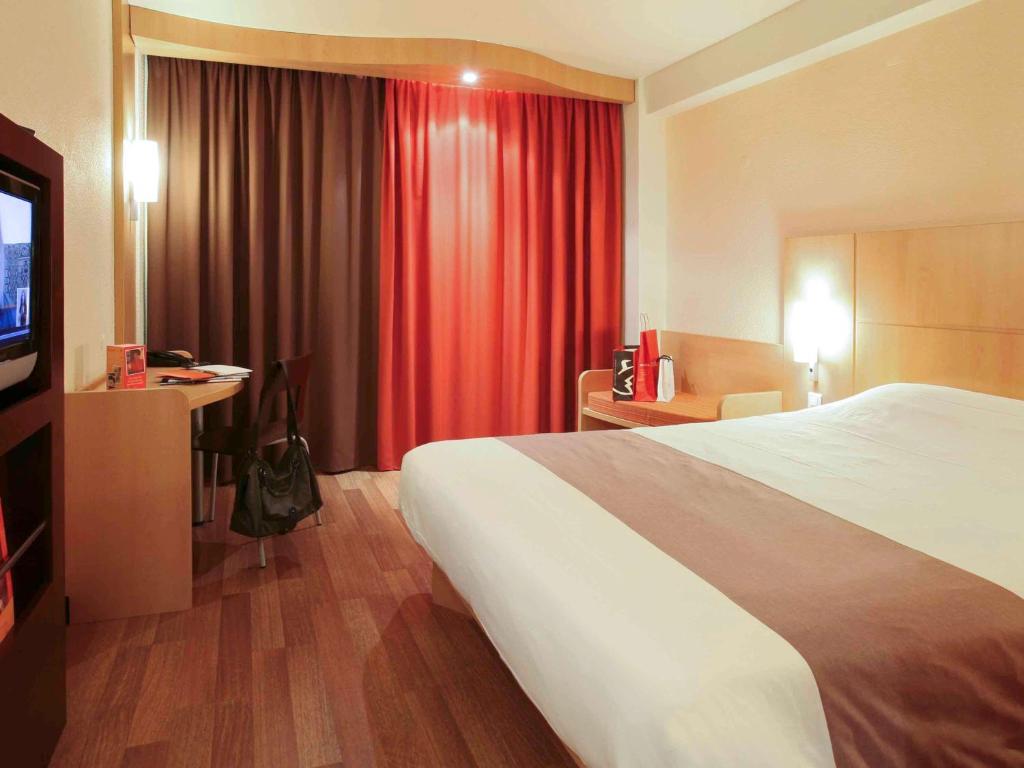 una camera d'albergo con un grande letto e una TV di Hotel ibis Braga a Braga