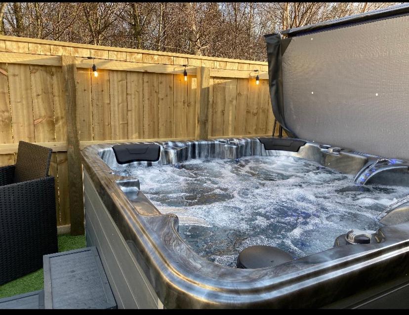 a hot tub with a waterfall in a backyard at Woodland Retreat in Swarland