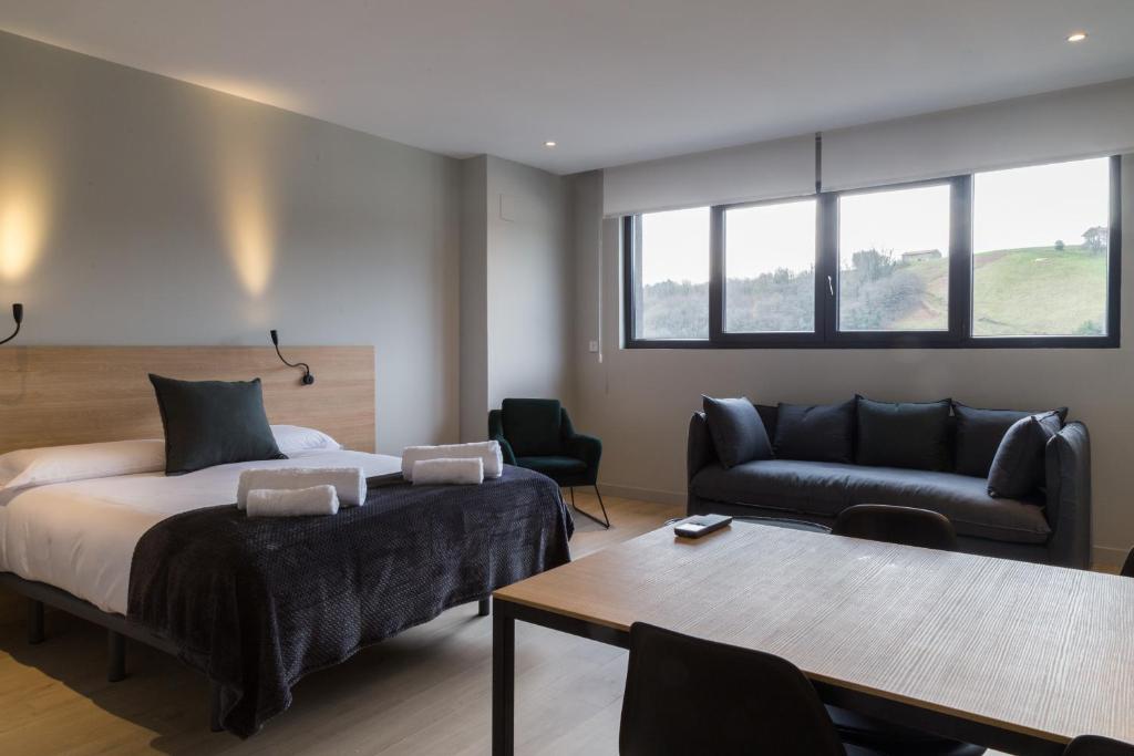 1 dormitorio con cama, sofá y mesa en Milimara Suites, en San Sebastián