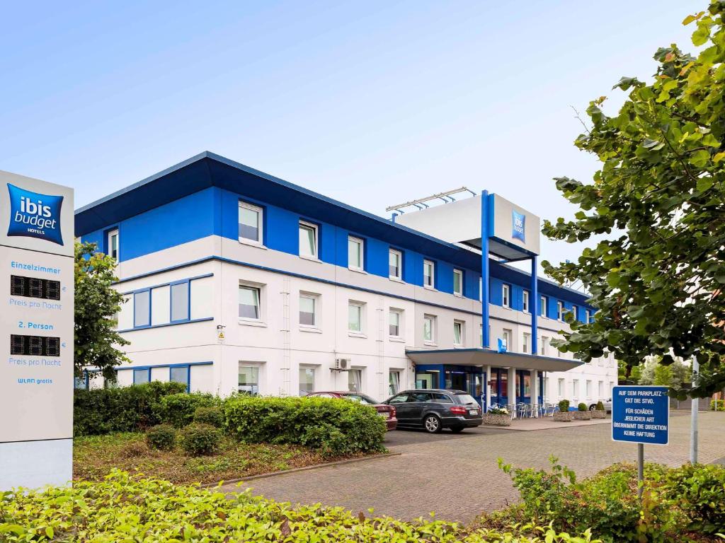 een groot blauw-wit gebouw met een parkeerplaats bij ibis budget Köln Marsdorf in Keulen