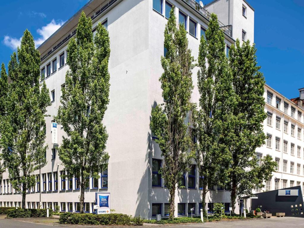 un edificio blanco con árboles delante de él en ibis budget Nürnberg City Messe en Núremberg