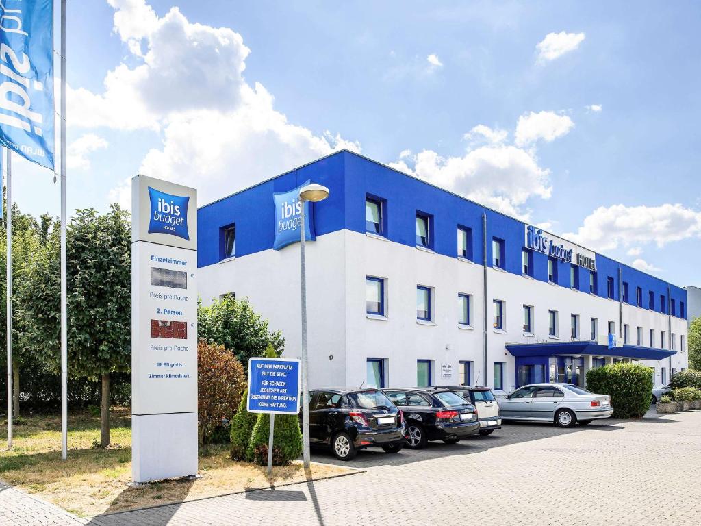 un edificio azul y blanco con coches estacionados frente a él en ibis budget Mainz Hechtsheim, en Mainz