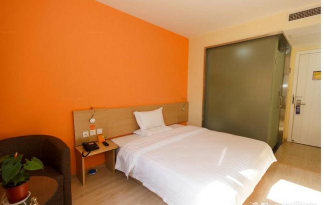 una camera con un letto bianco e una parete arancione di 7Days Inn Hangzhou Wanda Square a Hangzhou