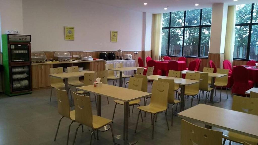 杭州市にある7 Days Inn (Hangzhou Xiaoshan Airport West Gate)のテーブル、椅子、赤い椅子が備わるレストラン