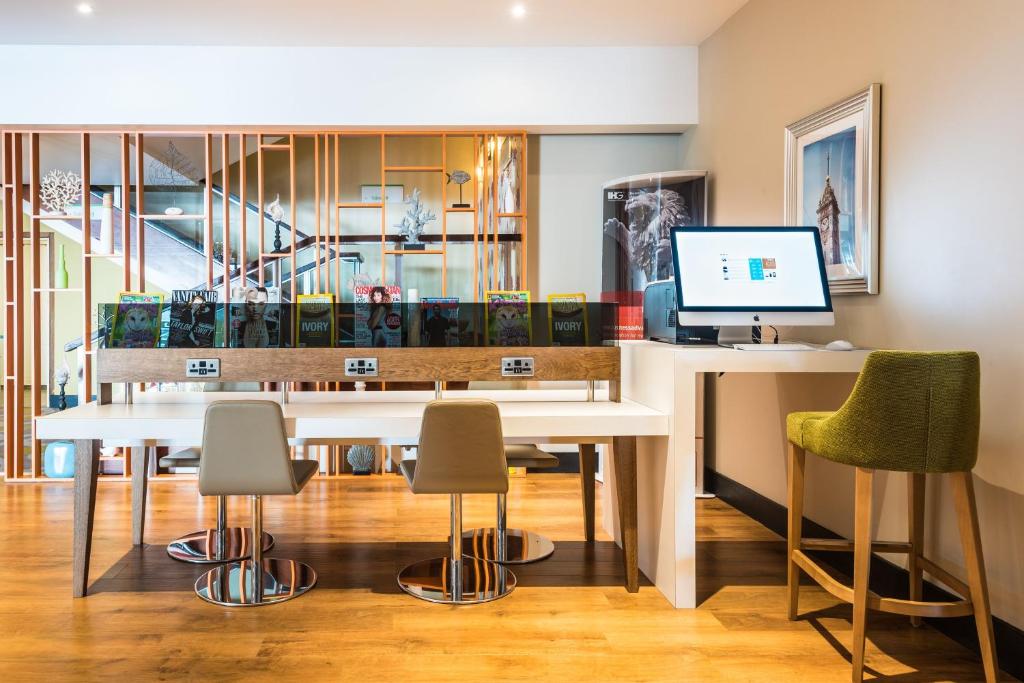 a dining room with a table with chairs and a computer at Holiday Inn Brighton Seafront by IHG in Brighton & Hove