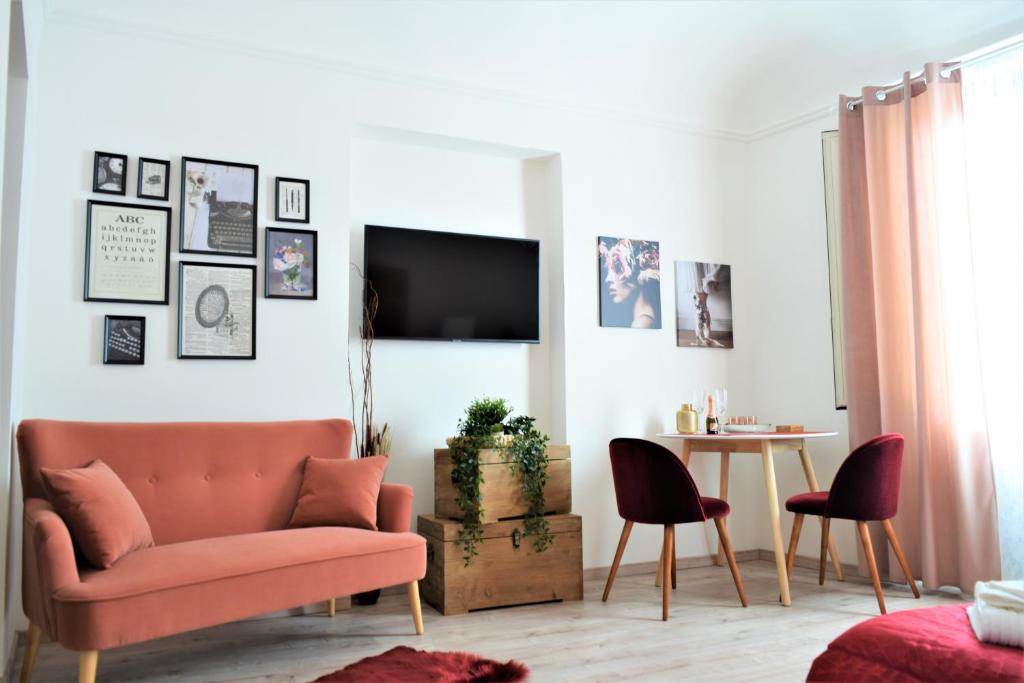 sala de estar con sofá rosa y mesa en Le Moresche Apartment, en Catania