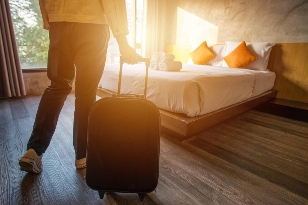 a person pulling a suitcase in a hotel room at Prusa 6 apartamenty in Wieluń