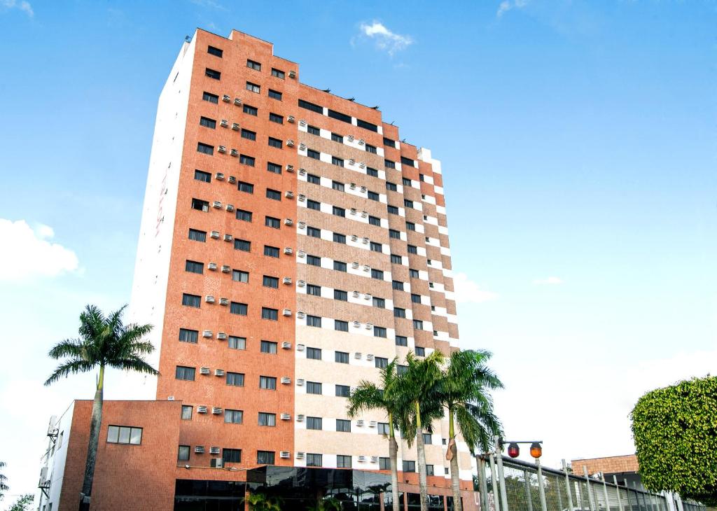 a tall building with palm trees in front of it at Hotel Londri Star in Londrina