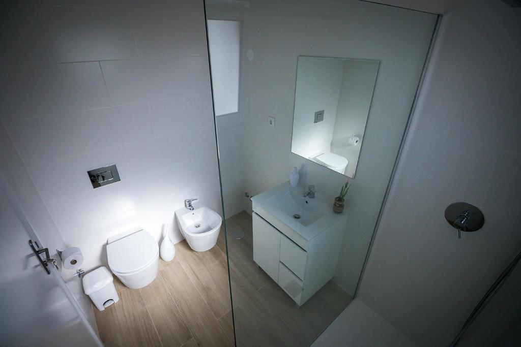 a white bathroom with a toilet and a sink at Ponta Delgada Guest House 2 in Arrifes