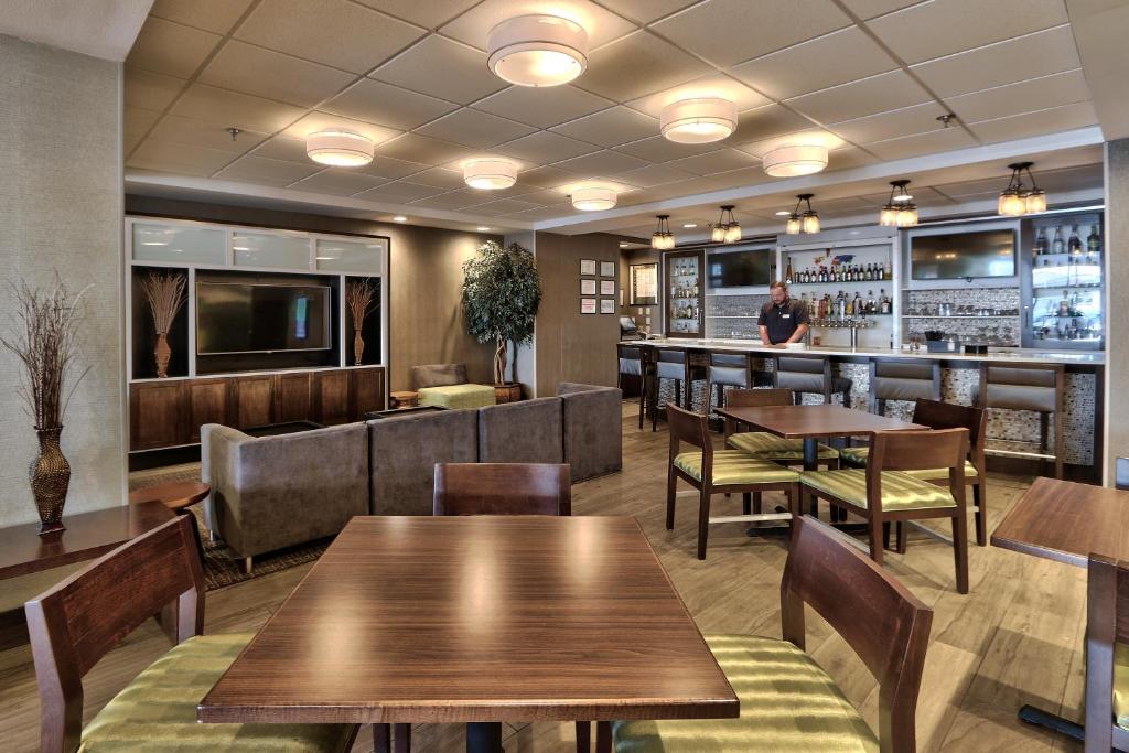 a restaurant with wooden tables and chairs and a bar at Holiday Inn & Suites Albuquerque-North I-25 by IHG in Albuquerque