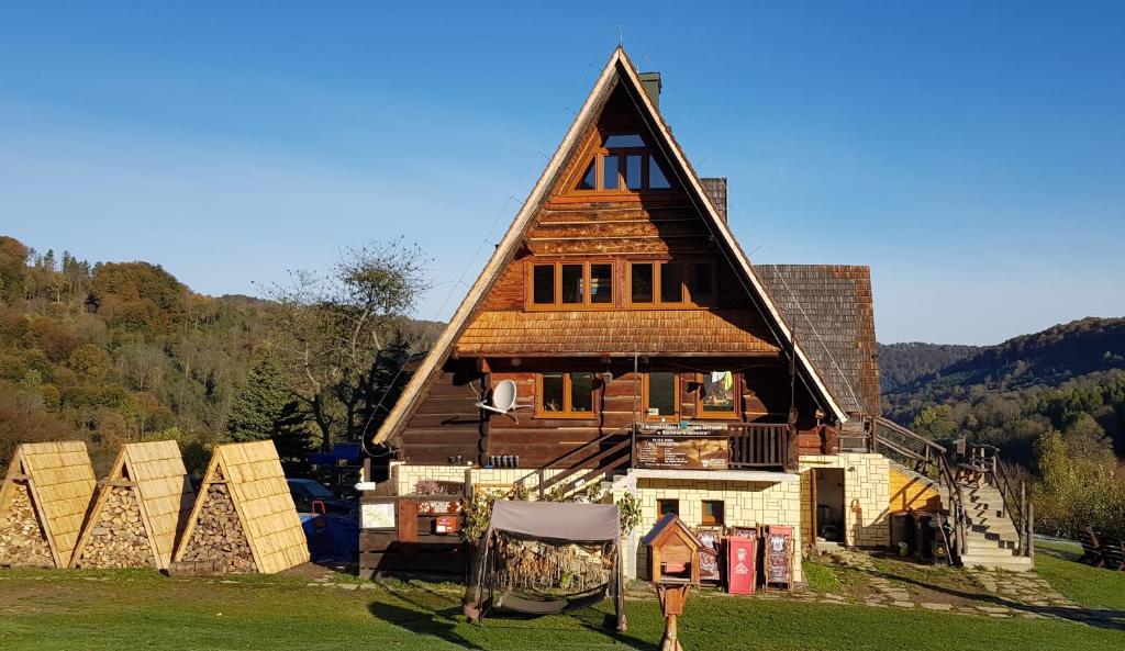 een groot huis met een rieten dak op een veld bij Bacówka PTTK Jaworzec in Wetlina