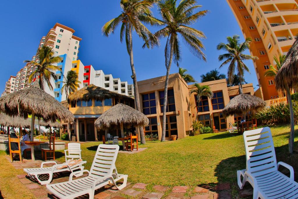un gruppo di sedie a sdraio e palme di fronte a un hotel di Villas El Rancho Green Resort a Mazatlán