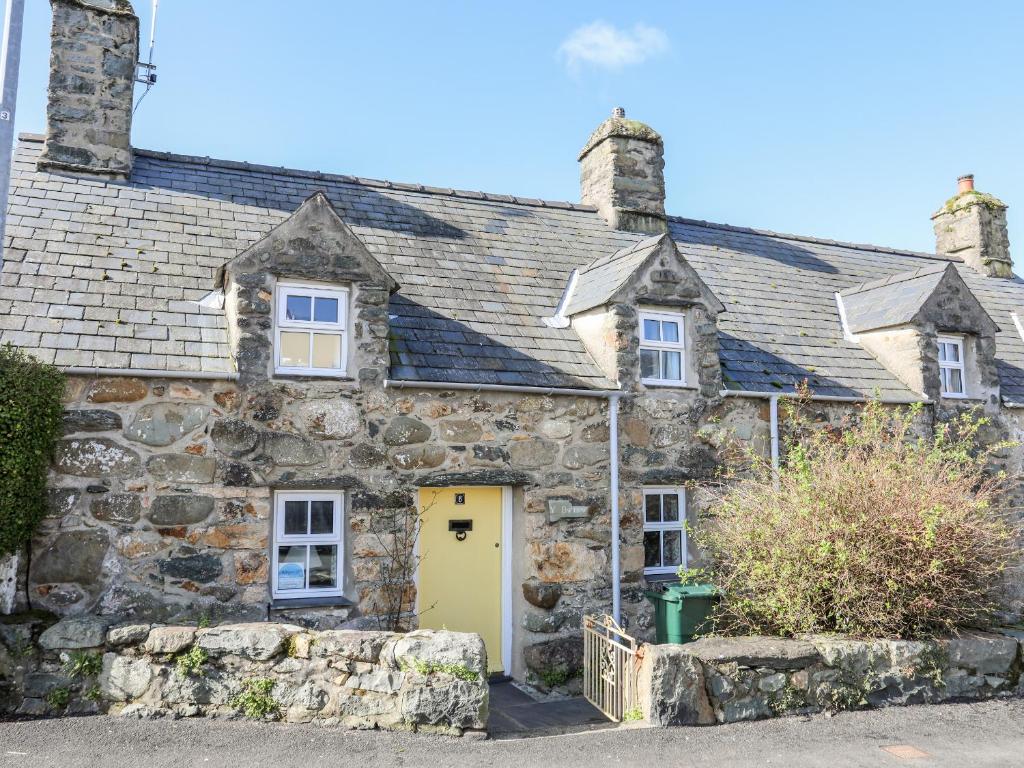 an old stone house with a yellow door at Y Bwthyn in Criccieth