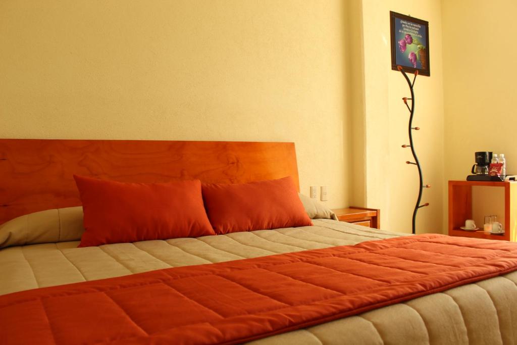 Tlaxcala de XicohténcatlにあるHotel Señorial Tlaxcalaのベッドルーム1室(大型ベッド1台、オレンジ色の枕付)