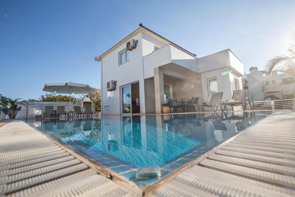 a house with a swimming pool in front of a house at Flouressia Villa 4 in Protaras