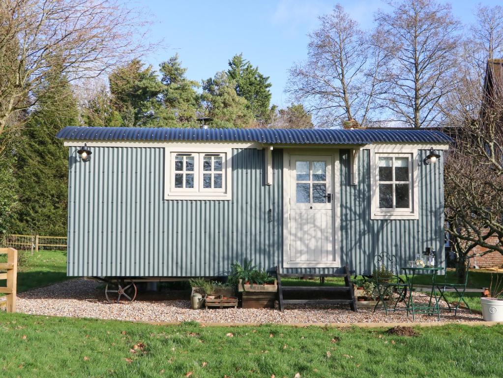 una casita azul y blanca en un patio en Gibson's Hut en Preston Candover