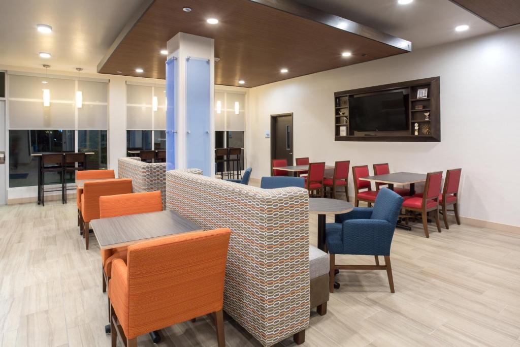 a restaurant with tables and chairs and a flat screen tv at Holiday Inn Express & Suites - Rapid City - Rushmore South by IHG in Rapid City