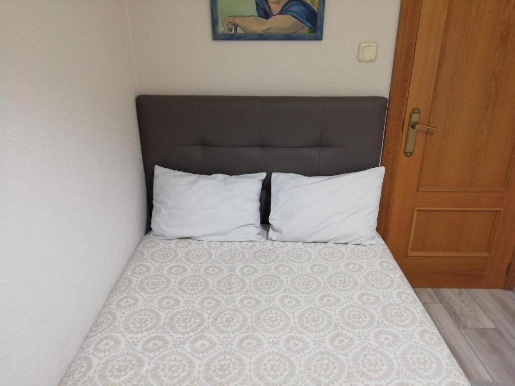 a bed with white pillows and a brown headboard at Monsalve10 in Zamora