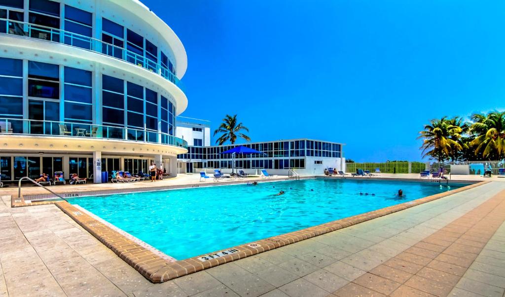 a large swimming pool in front of a building at Ocean view studio with direct beach access and a shared pool & tennis court! in Miami Beach