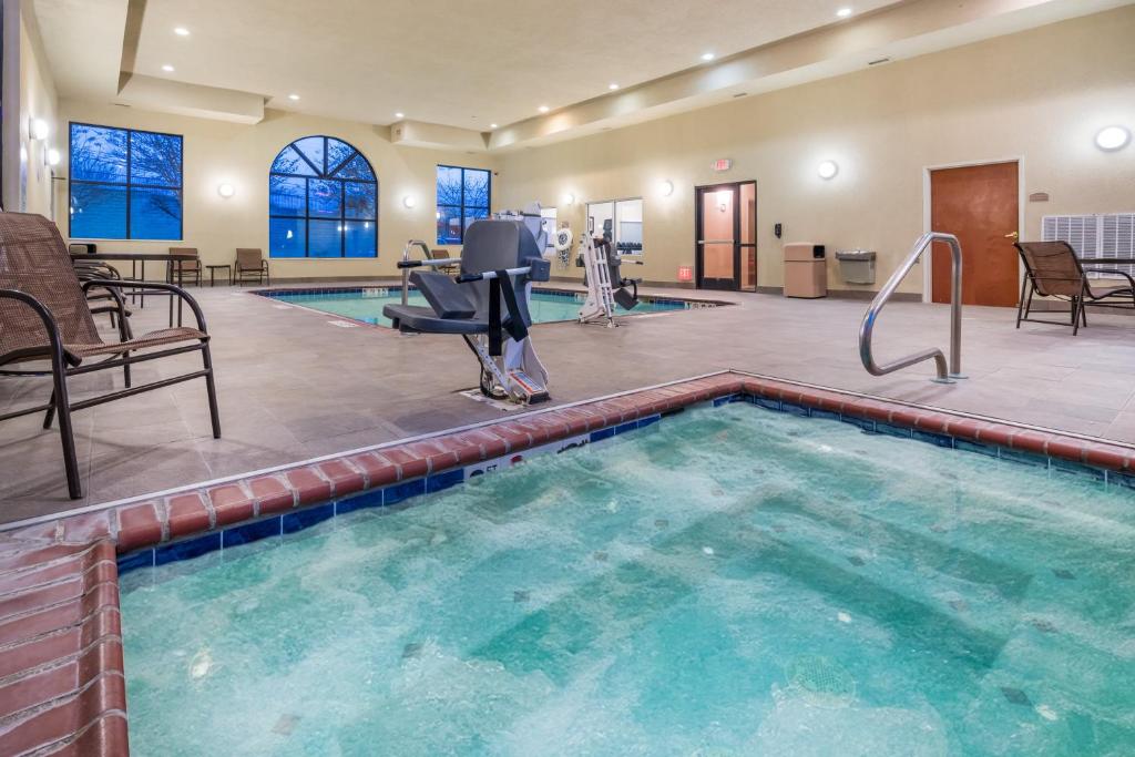 a pool in a fitness center with chairs and tables at Holiday Inn Express & Suites Rocky Mount Smith Mountain Lake, an IHG Hotel in Rocky Mount