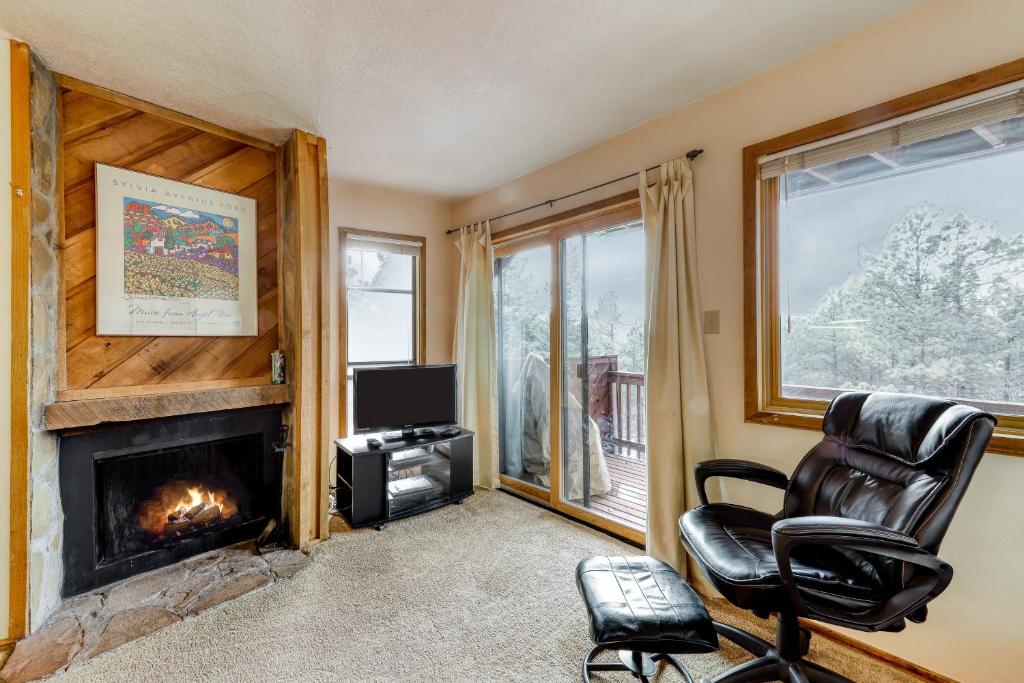 a living room with a fireplace and a chair at Lift Condos in Angel Fire