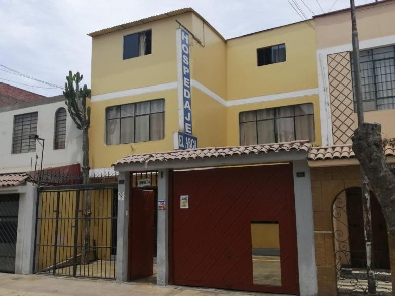 un edificio amarillo con un garaje rojo delante de él en Hospedaje El Arca, en Lima