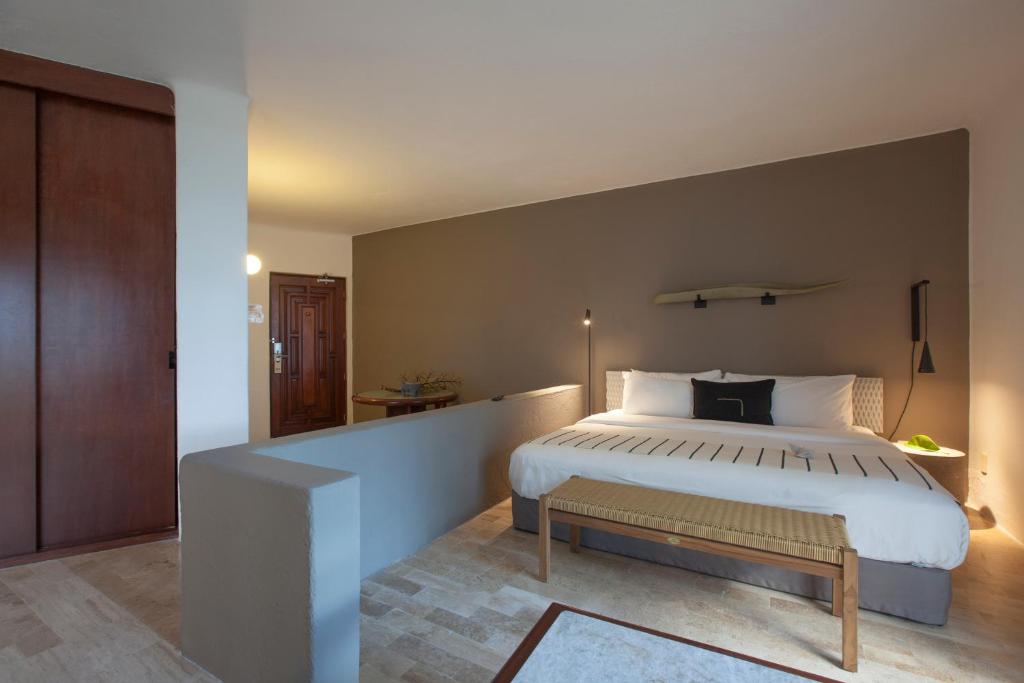 a bedroom with a large bed with a bench next to it at Gaviana Resort in Mazatlán