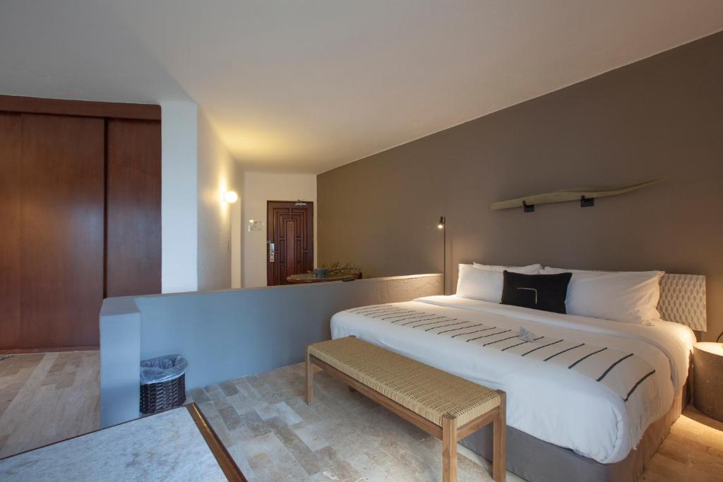a bedroom with a large white bed and a bench at Gaviana Resort in Mazatlán