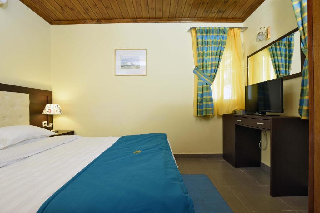 a hotel room with a bed and a television at Haus Platanos Apartments & Bungalows by the Sea in Vourvourou