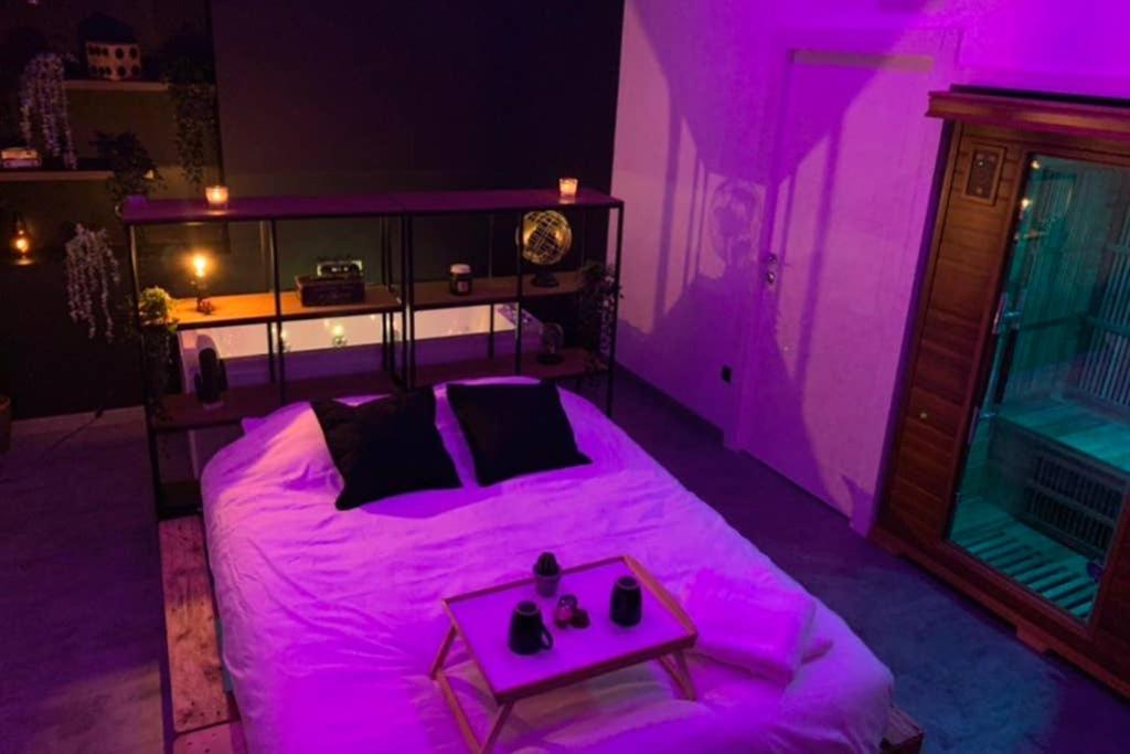 Cette chambre violette comprend un lit et une table. dans l'établissement Appartement Spa - NAHLEO Industriel, à Dole