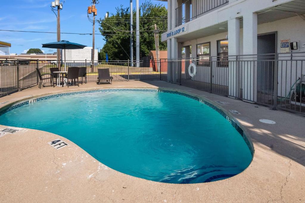 une piscine en face d'un bâtiment dans l'établissement Motel 6 Irving - Loop 12, à Irving
