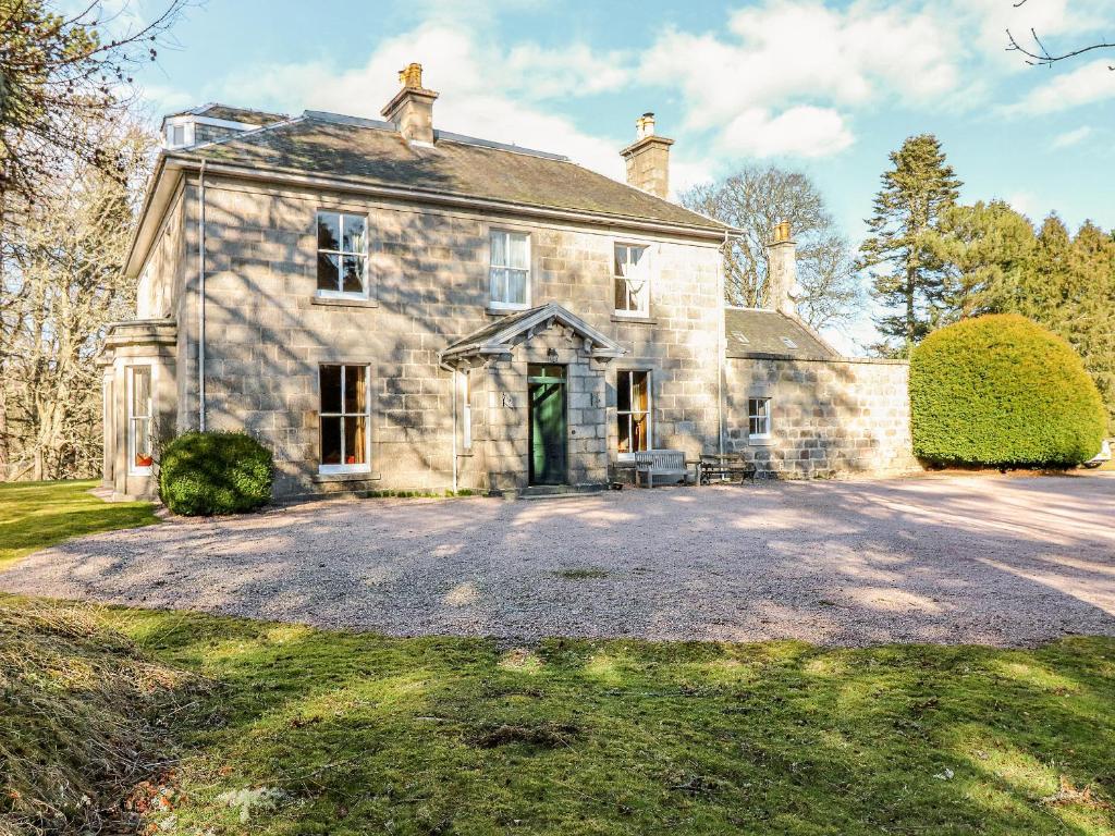 een oud stenen huis met een grote oprit bij Inverallan House in Grantown on Spey