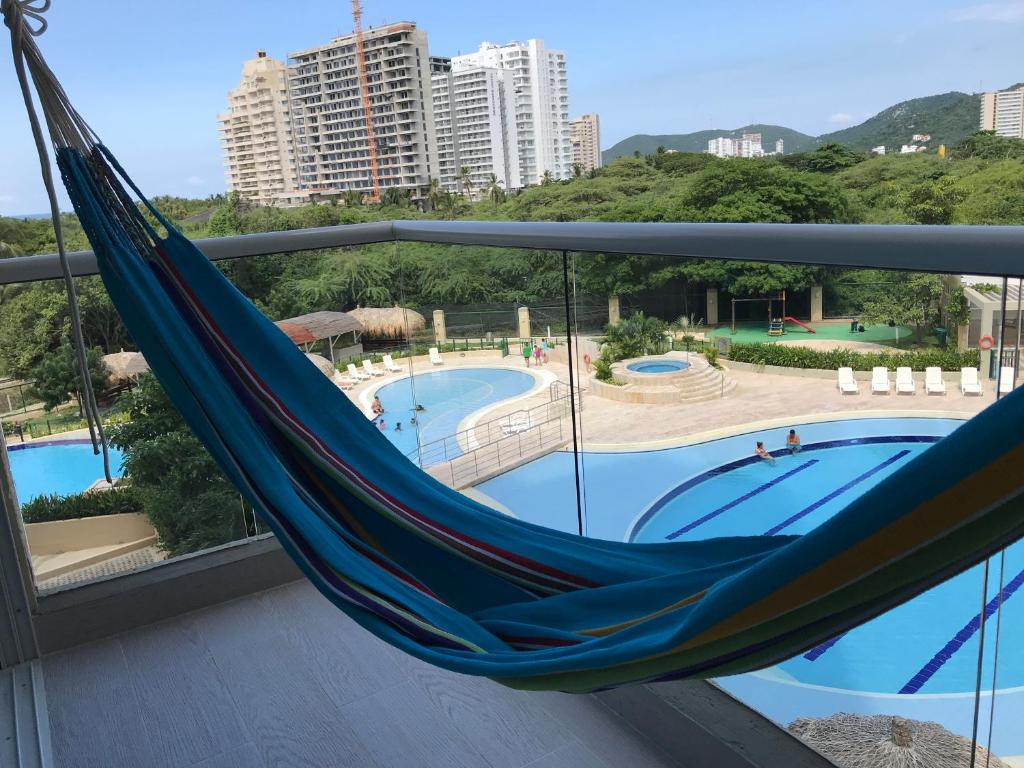 a blue hammock on a balcony next to a pool at SANTA MARTA OASIS en ZAZUE in Santa Marta