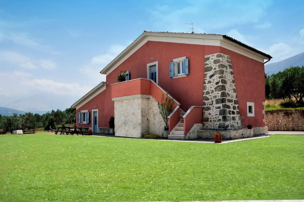 un edificio rojo con un campo de hierba delante de él en La Masseria di Villa Giulia, en Tocco da Casauria
