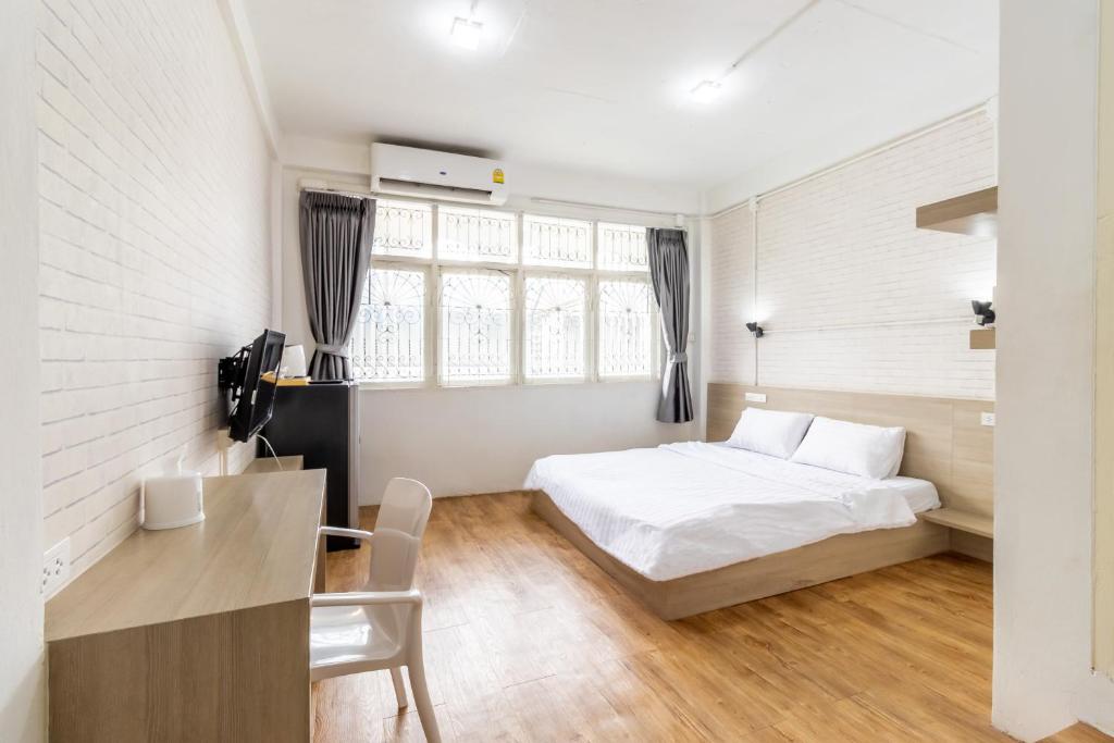 a bedroom with a bed and a table and a desk at Ze Residence Bang Aor Station in Bangkok