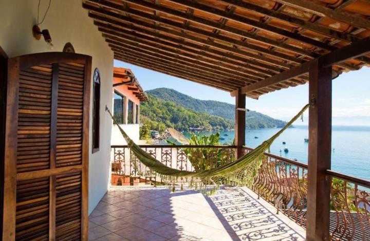 een balkon met een hangmat en uitzicht op de oceaan bij Casa Ilha Grande in Praia de Araçatiba