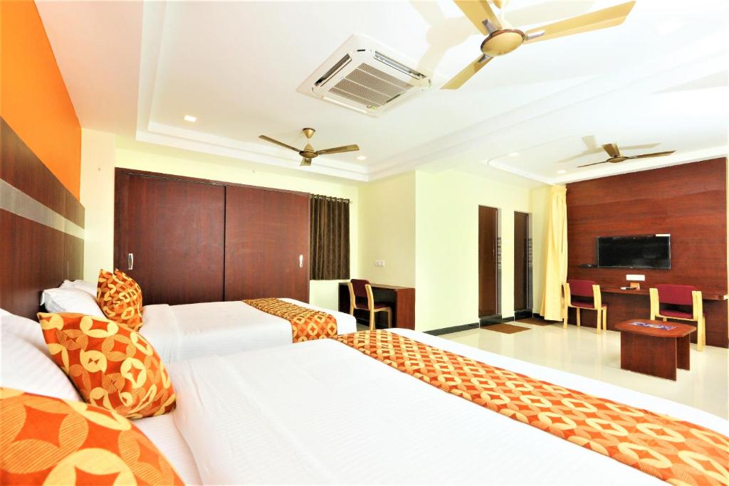 a hotel room with two beds and a television at Hotel Ramcharan Residency, Tirupati in Tirupati