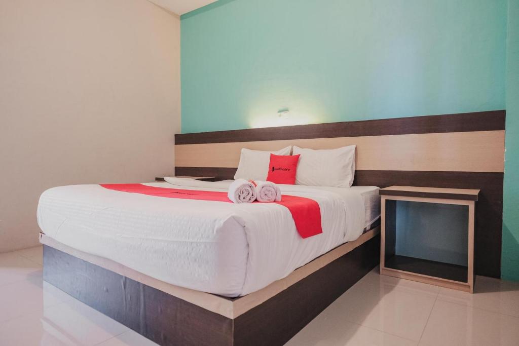 a bedroom with a large bed with two towels on it at RedDoorz Syariah at Hotel Grand Mentari in Bengkulu