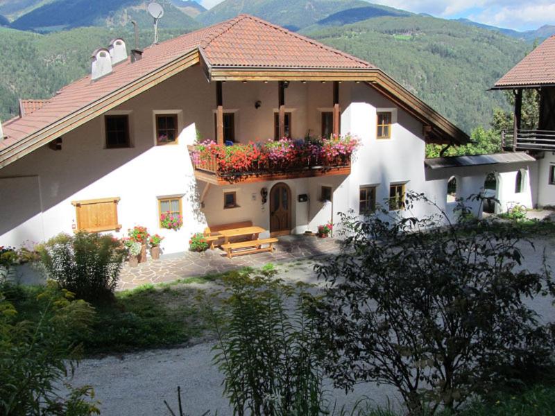 a large white house with a bench and flowers at Appartements Lindenhof in Vandoies