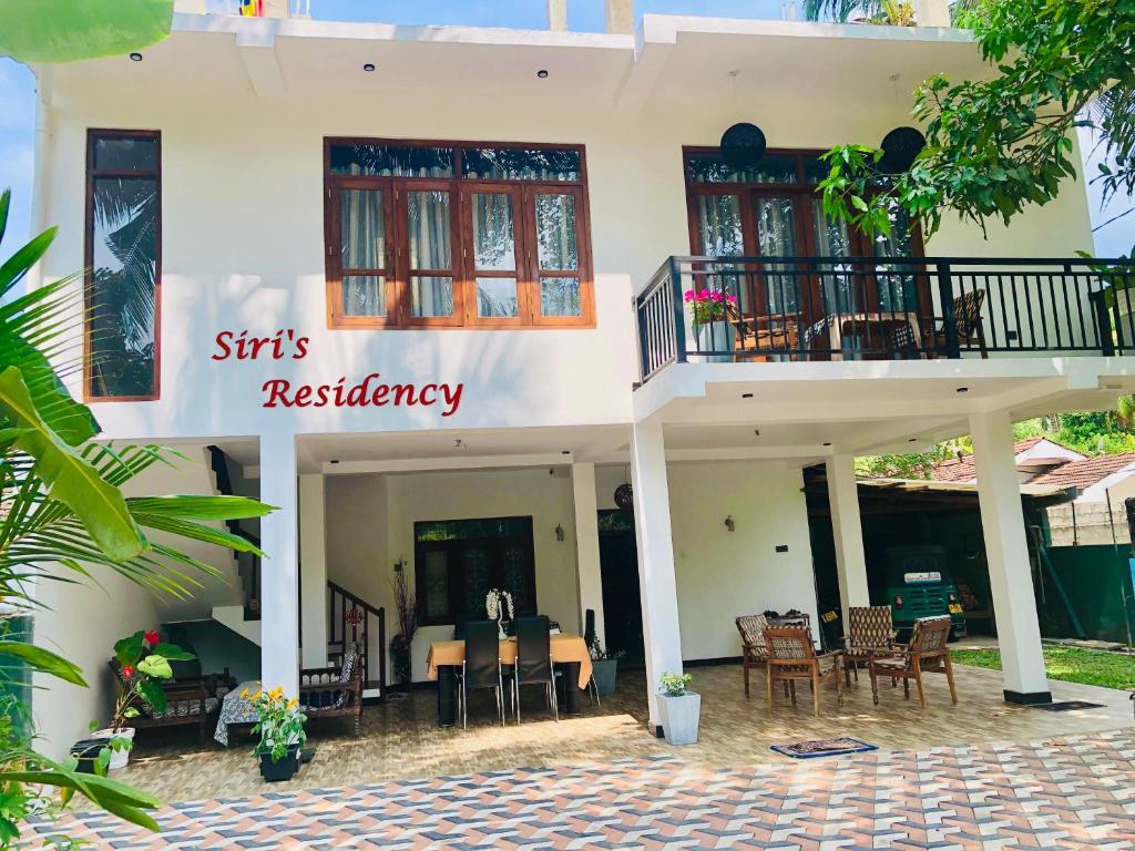 a house with a balcony and tables and chairs at Siri's Residency in Habaraduwa