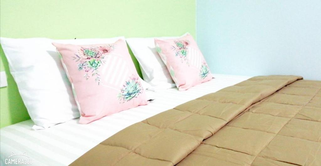a bed with pink and white pillows on it at Khao Thong Home Stay in Krabi town