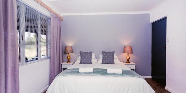 um quarto com uma grande cama branca e 2 candeeiros em Konings Cottage em Gansbaai